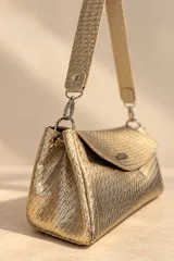 Cartera de mano Pecari modelo Bea, confeccionada en cuero vacuno con textura tejida color dorado. Presenta solapa frontal con broche imantado y placa metálica con el logo de la marca, además de una correa larga para el hombro.