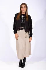 Falda midi color beige de simil cuero, con corte irregular, bolsillo lateral y cinturón con hebilla plástica.