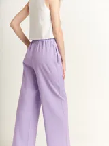 Pantalón de lino color lila, tiro alto, corte palazzo con elástico en la pretina, bolsillos laterales y dobladillo invisible.