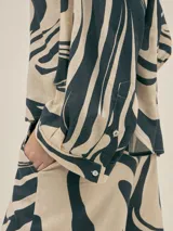 Conjunto de camisa y pantalón de lino color verde con estampado de flores blancas. La camisa es de manga larga y corte holgado.