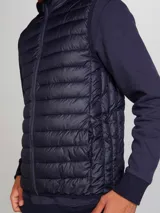 Chaleco puffer color verde oliva con cierre frontal y bolsillos laterales.