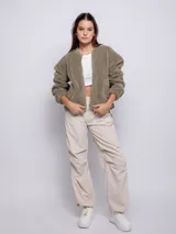 Canguro verde con cuello tipo bomber, de textura peluda y polar por dentro. Posee dos bolsillos laterales y cierres de nylon a tono, también en los laterales.