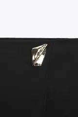 Falda pantalón corta de tiro alto con estampado animal print, cierre lateral oculto y aplique metálico triangular en la parte delantera.