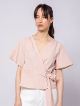Blusa color rosa pálido con escote en V, mangas cortas tipo kimono y lazo para atar en la cintura. Confeccionada en tela con textura acanalada.