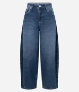 Pantalón de jean con corte barrel, de cintura alta y estructura amplia con piernas voluminosas que se cierran ligeramente en el ruedo. Presenta cierre tradicional, trabillas para cinturón y bolsillos funcionales.