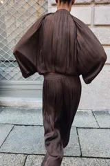 Pantalón de tiro alto con diseño abullonado, confeccionado en tejido satinado con acabado plisado y puños elásticos en los tobillos.