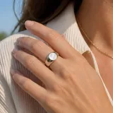 Anillo de acero quirúrgico de diseño esclavo con una incrustación circular de nácar en el centro.