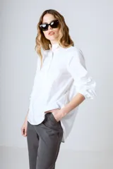 Camisa blanca de corte holgado, cuello mao y mangas largas con puños fruncidos.