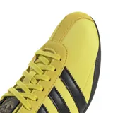 Championes urbanos Adidas modelo Tokyo, color amarillo con las icónicas tres tiras laterales en negro. Presentan un diseño de perfil bajo con suela de goma negra y detalles en gamuza en la zona de los cordones y el talón.