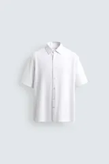 Camisa blanca de manga corta, corte regular fit, con cuello italiano y cierre frontal de botonadura.