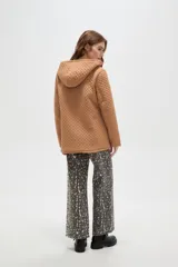 Campera de diseño capitoneado con cierre frontal, capucha integrada y bolsillos laterales. Presenta un corte entallado y mangas largas.