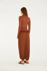Pantalón de tiro alto y silueta amplia, estilo aladín, color marrón. Cuenta con cintura de pala ancha fruncida, bolsillos laterales y puños elásticos en los tobillos.