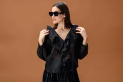 Camisa negra de manga larga con volados frontales y cuello en V. Presenta puños elásticos y una caída fluida.