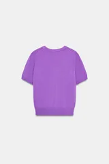 Jersey de punto fino con cuello redondo y manga corta, con terminaciones en rib en cuello, mangas y ruedo.