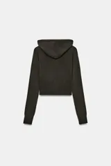 Sudadera cropped de punto con cierre frontal de cremallera metálica, capucha ajustable con cordones y mangas largas con puños en rib.