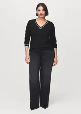 Jersey de punto fino de manga larga en color negro, con cuello en V y detalles de líneas blancas en contraste en el cuello y los puños.