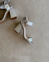 Sandalia de taco cuadrado alto, con diseño de punta cuadrada, tira delantera ancha y tira ajustable en el tobillo con hebilla metálica.