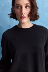 Sweater blanco de punto con diseño holgado, cuello redondo, mangas largas acampanadas y detalles de textura horizontal en el tejido.