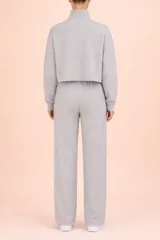 Conjunto de dos piezas en tejido de punto acanalado color gris. Incluye un buzo de corte cropped con cuello alto y cierre frontal, y un pantalón de corte recto con cintura elástica.