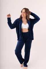 Conjunto de dos piezas confeccionado en tela plush, compuesto por una campera con cierre frontal y cuello alto, y un pantalón de corte recto. Presenta un diseño minimalista y cómodo en color gris claro.