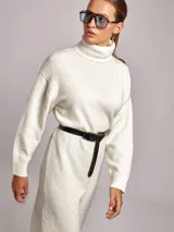 Vestido midi de punto con cuello alto tipo poleron, de corte holgado y mangas largas con puños acanalados. Presenta un diseño en color blanco con sutiles motas de colores.
