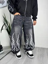 Jean baggy de corte ancho y relajado, color negro con efecto lavado ácido y estampado de cadenas blancas en la parte inferior de las piernas.