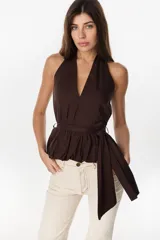 Blusa marrón de diseño halter con escote en V pronunciado, corte cruzado y lazo ajustable en la cintura con caída lateral.