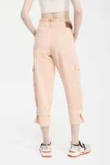 Pantalón capri color melocotón, de tiro alto con cintura elastizada y cuatro botones, bolsillos cargo laterales con solapa y ajuste con hebilla en los tobillos.