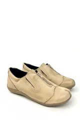 Zapato bajo color beige de cuero con cierre de cremallera frontal.