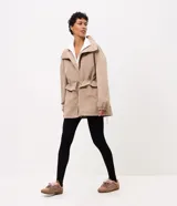 Campera cortaviento oversized color beige, de cuello alto, mangas largas con puños elásticos, bolsillos frontales con solapa y cordón ajustable en la cintura.