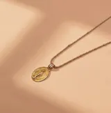 Conjunto de cadena y dije de la Virgen Milagrosa, elaborado en plata y oro. La cadena presenta un diseño de eslabones texturizados y el dije es de forma ovalada con relieve.