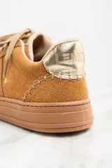 Zapatillas bajas color marrón claro, confeccionadas en gamuza con detalles en cuero dorado en el talón.
