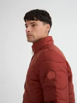 Campera capitoneada color ladrillo, con cuello alto, cierre frontal y bolsillos laterales con cierre.