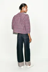 Blusa de cuello redondo y manga larga abullonada, con estampado de cuadros en tonos rosados, violetas y blancos. Cierre frontal con botones.