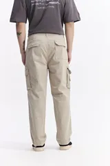 Pantalón cargo de corte baggy, color beige, con bolsillos laterales tipo cargo con cierre y solapa, y diseño de pierna ancha.
