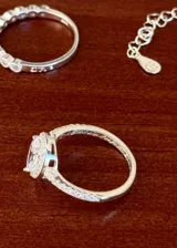 Conjunto de joyería de tres piezas en plata 925 y zirconias, compuesto por una pulsera con cadena y zirconias colgantes, un anillo medio sin fin con zirconias y un anillo solitario con zirconias en corte gota y pavé lateral.