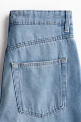 Jean de tiro alto con corte recto y holgado, confeccionado en denim rígido de cinco bolsillos con cierre de botón.