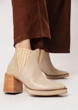 Botín de cuero color beige con textura reptil, elástico lateral y cierre interno. Tiene plataforma delantera y taco de madera.