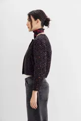 Campera bomber corta a la cintura con cuello redondo, confeccionada en jacquard con estampado de leopardo en tonos morados y marrones. Presenta una cartera frontal con cierre adornada con piedras y strass.