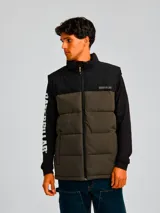 Chaleco acolchado bicolor con diseño de bloques en negro y verde oliva. Presenta cierre frontal completo, cuello alto, bolsillos laterales con cierre y logo de la marca estampado en el pecho.