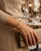Esclava rígida de acero con baño de oro, con diseño grabado en relieve en toda su superficie.