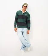Remera tipo chomba de manga larga, con bloques de color en tonos verde y azul marino, cuello polo blanco y pequeño bordado en el pecho.