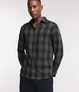 Camisa de hombre de manga larga, confeccionada en franela de algodón, con cuello inglés y abotonadura frontal. Presenta un estampado de cuadros grandes en tonos verde oliva y negro.