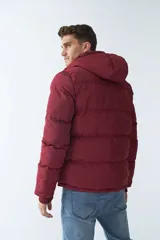 Campera puffer color bordó, con capucha ajustable y cierre frontal con cremallera.