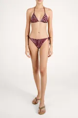 Calzón de bikini con tiras laterales ajustable, con estampado animal print tipo cebra en tonos bordó y rosado, y detalle de cuentas en los extremos de los cordones.