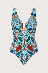 Malla enteriza con escote en V profundo y detalle de herraje metálico en el centro del busto. Presenta un estampado geométrico y floral en tonos azul, terracota y blanco.