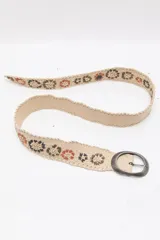 Cinturón de cuero beige con aplicaciones de rafia trenzada y diseño floral bordado. Cuenta con hebilla ovalada de metal envejecido y cierre regulable.