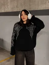 Sweater negro con cuello redondo y diseño geométrico en gris en la parte superior del pecho y hombros.