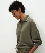 Buzo cerrado de algodón con cuello polo, mangas largas con puños ajustados y detalle de líneas contrastantes en el cuello.