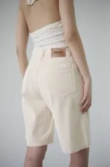 Bermuda de denim azul claro, de tiro medio y largo a la rodilla, con calce relajado y silueta amplia. Cuenta con bolsillos delanteros y traseros, y cierre frontal con botón y cremallera.